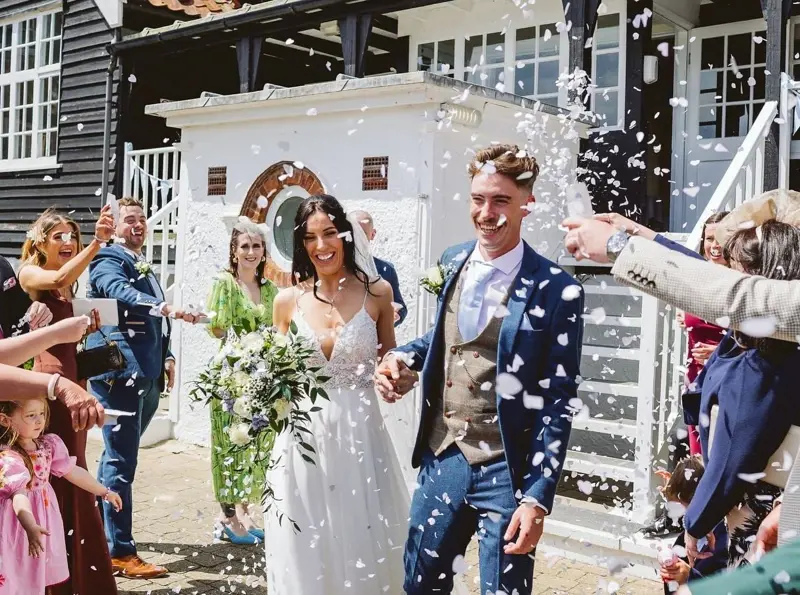 Bride and Groom under confetti with guests around