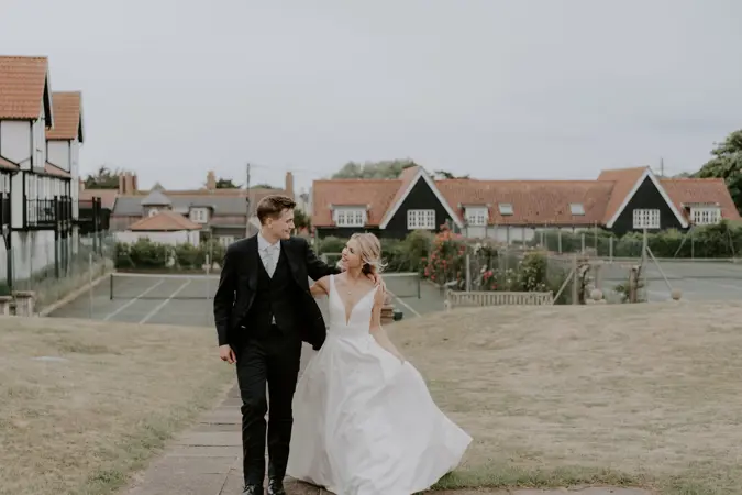 Couple walking on back lawn by tennis courts at Thorpeness Country Club
