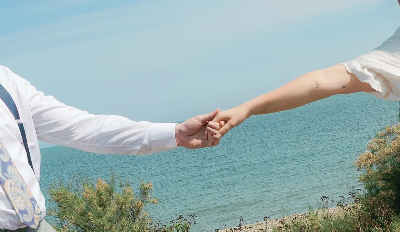 Bride and groom holding hands in front of the sea