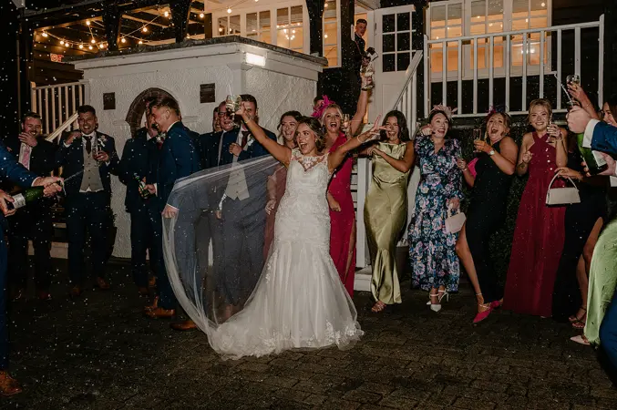 Couple and wedding party spraying champagne