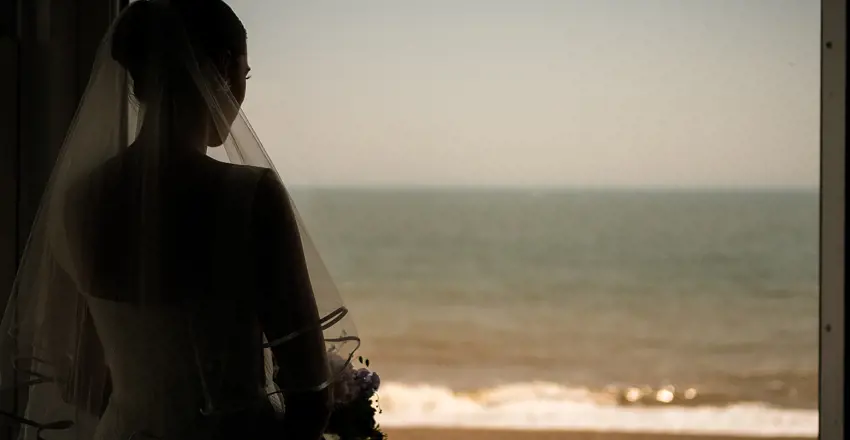 Bride, Bina, looking out of seaview window